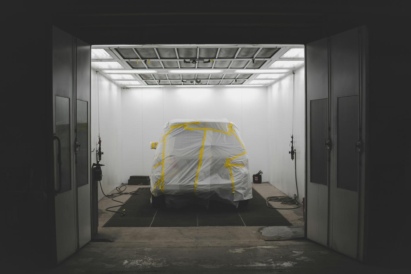 A car inside a clean, brightly lit professional spray booth